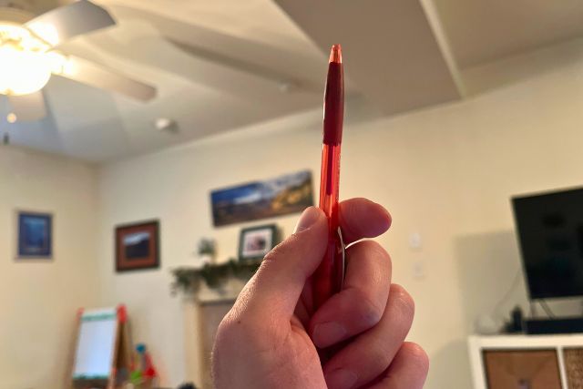 My Italian hand holding up a red pen.